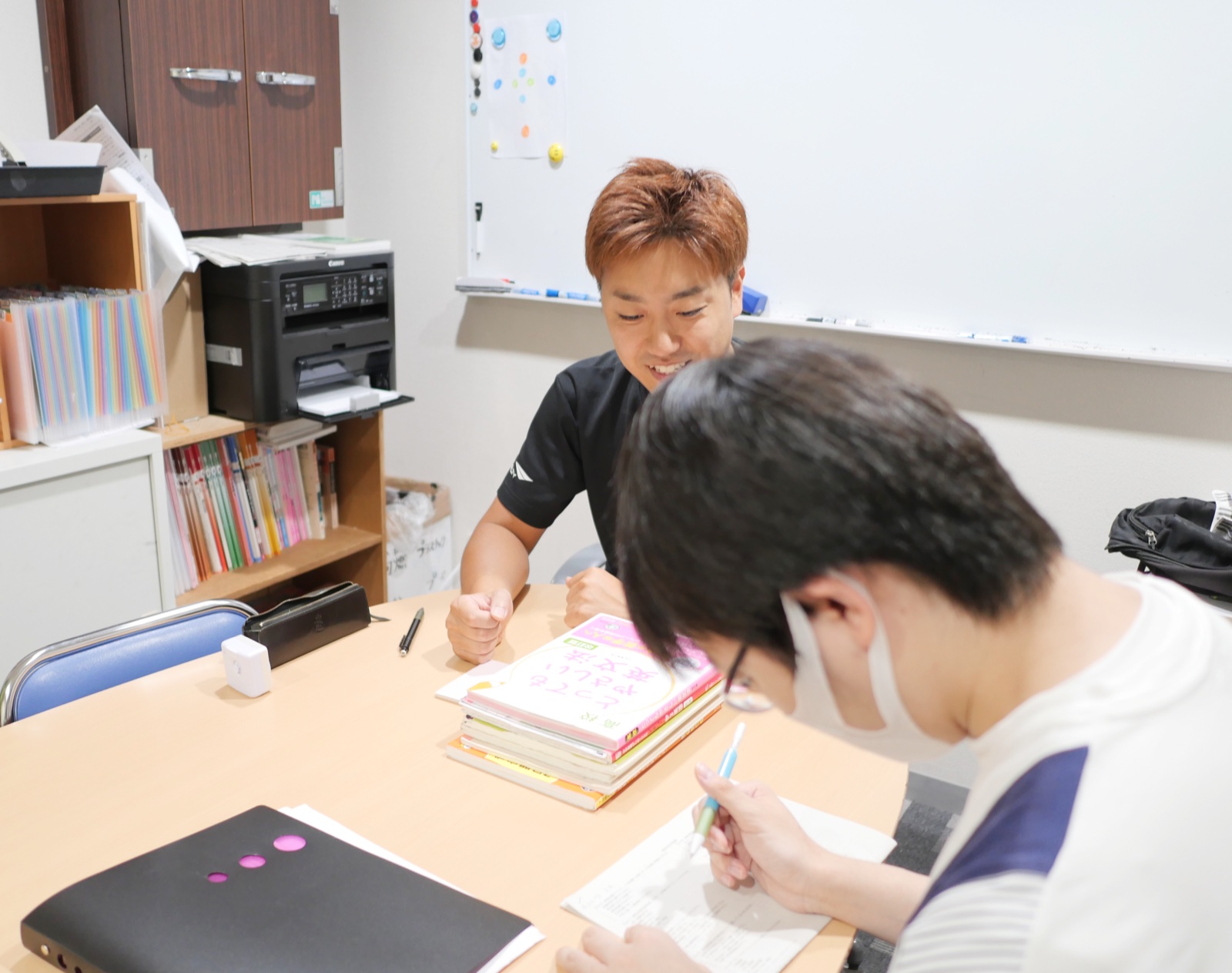 講師が塾生とノートを見ながら学習内容を話し合う様子