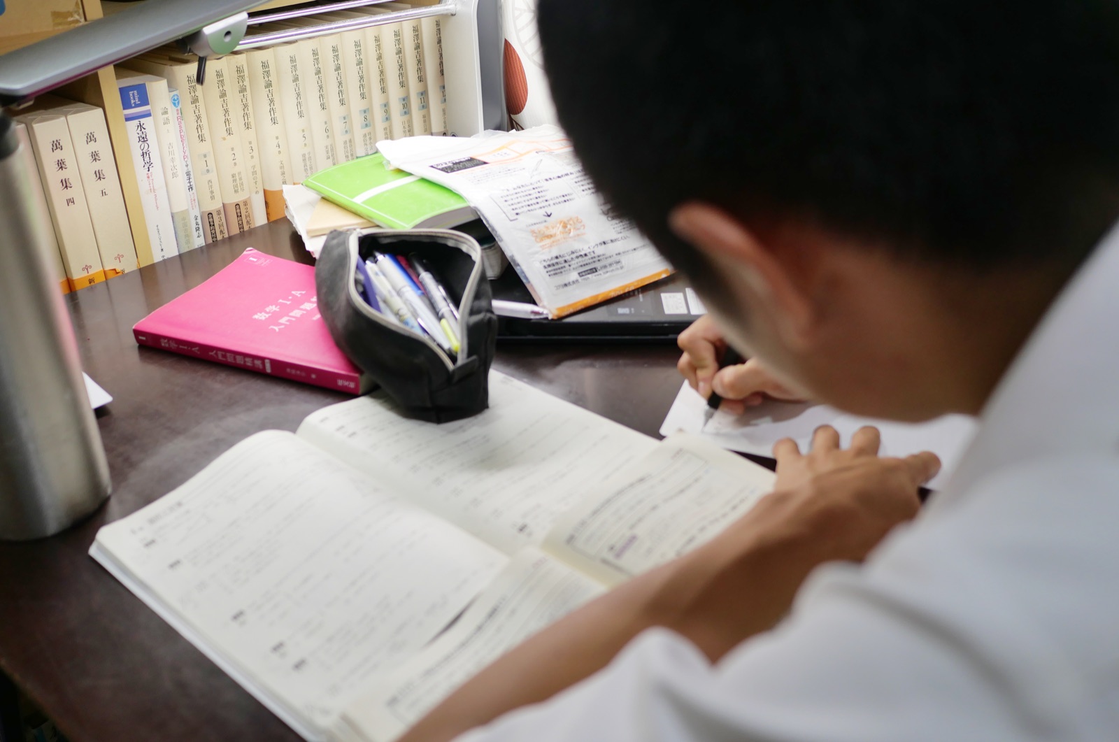 塾で教材を開いて学習する生徒